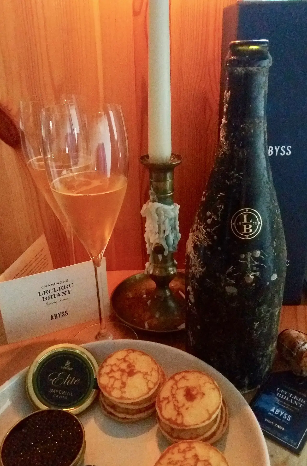Denkhenk — CC BY-SA 4.0 A bottle of Leclerc Briant Abyss Champagne beside glasses and its presentation box