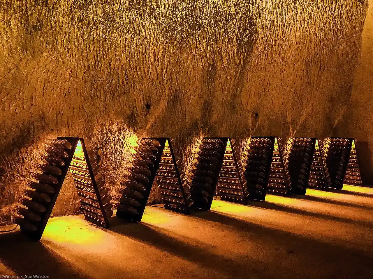 Riddling racks holding Champagne bottles inside Ruinart’s chalk cellars